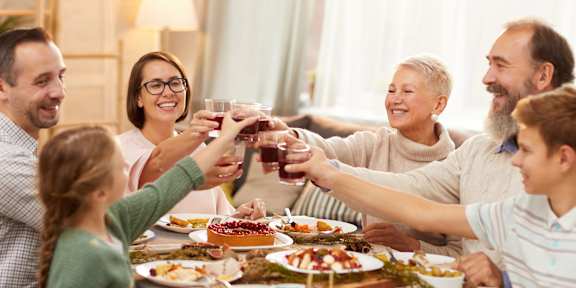 A group of people toasting with drinks at a dinner table.