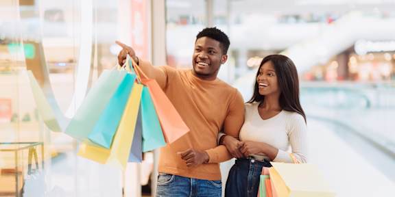A man and woman are standing in a store holding shopping bags.