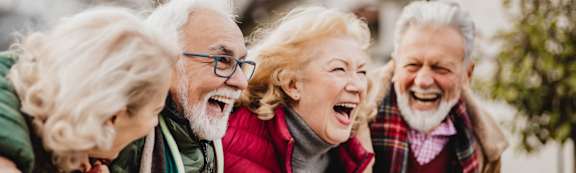 A group of elderly people are laughing together outside.