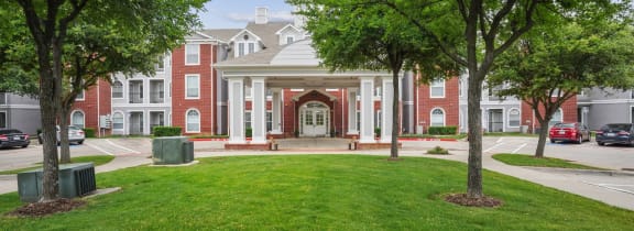 a large building with a lawn and trees in front of it