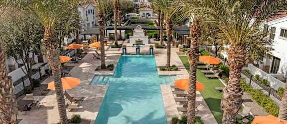 A pool surrounded by palm trees and orange umbrellas.