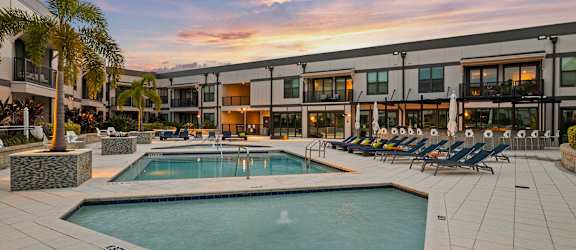 Rooftop fire pit with blue lounge chairs next to resort style pool. Live at The Morrison SoHo located near Hyde Park and Downtown Tampa.