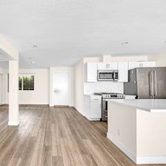 an open kitchen and living room with white walls and wood floors