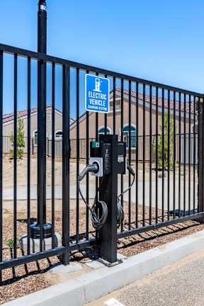 A black metal fence with a sign that says "Electric Vehicle" on it.