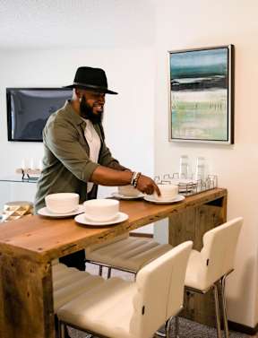 A man in a hat is setting a table with a woman standing behind him at Rosemont Place Apartments, Des Moines, IA, 50320