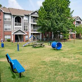 a large grassy area with a playground and picnic tables in front of an apartment complex at Lincoln at Wolfchase Apartments, Tennessee