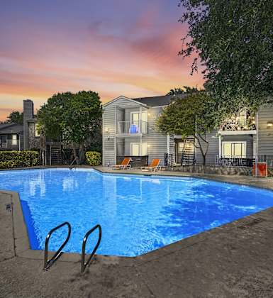 A swimming pool surrounded by a fence and a building in the background.