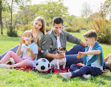 a family of four sitting on the grass with a dog