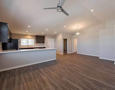 A spacious room with wooden flooring and a ceiling fan.