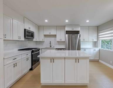 A modern kitchen with white cabinets and stainless steel appliances.