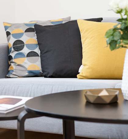 a living room with a couch and a table with a vase and some pill