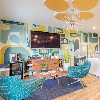a living room with blue chairs and a table and a television