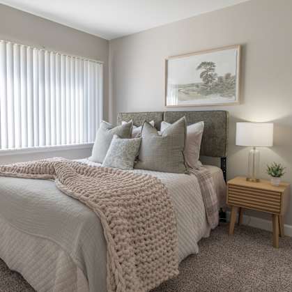 A bedroom with a large bed covered in a white blanket and pillows.