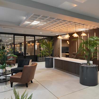 a lobby with a reception desk and chairs and plants