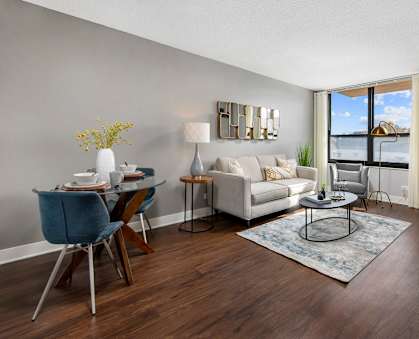 A living room with a white sofa, a glass table, and a grey wall.