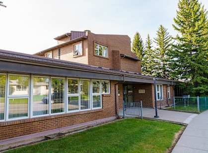 a brick building with large windows and a grassy area in front of it