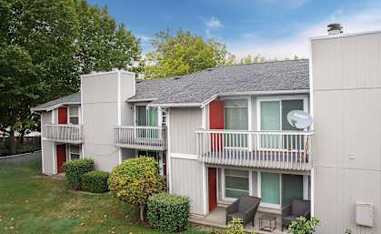 A small white house with a red door and a balcony.