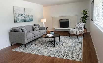 A living room with a grey couch, a coffee table, and a painting on the wall.