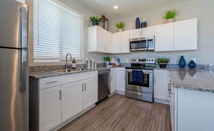 A modern kitchen with white cabinets and stainless steel appliances.