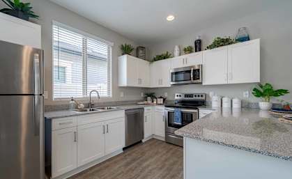 A kitchen with white cabinets and a granite countertop.