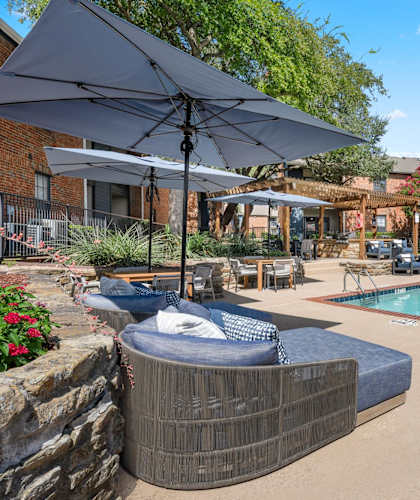 A pool with a hot tub and umbrellas in a backyard.