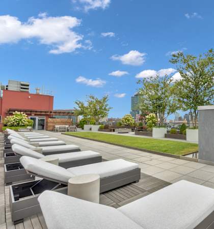 a rooftop patio with white couches and a grassy area and a wooden fence
