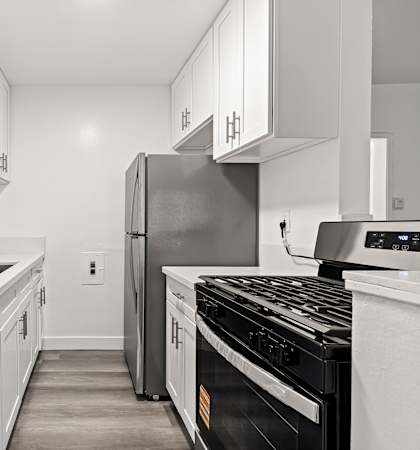 A modern kitchen with white cabinets and stainless steel appliances.