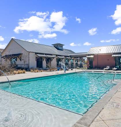 A large outdoor swimming pool with a metal roofed building in the background.