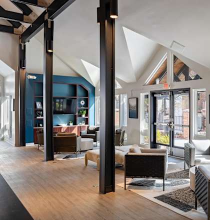 A modern living room with a high ceiling and large windows.