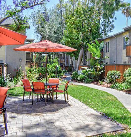 A patio with a table and chairs is surrounded by a garden.