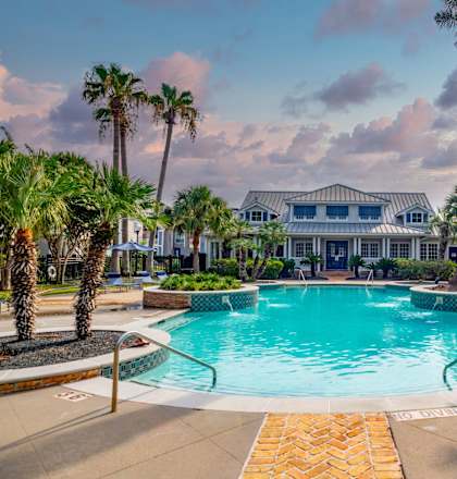 a swimming pool with palm trees and a house in the background