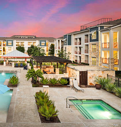 a swimming pool with chairs and umbrellas in front of an apartment building