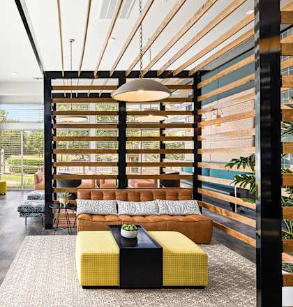 a lounge area with a couch and tables in a room with large windows