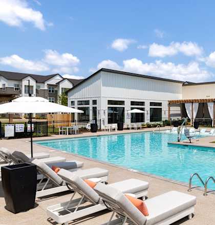 a swimming pool with lounge chairs in front of a building