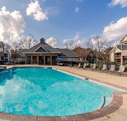 A large swimming pool in the middle of a resort surrounded by chairs.