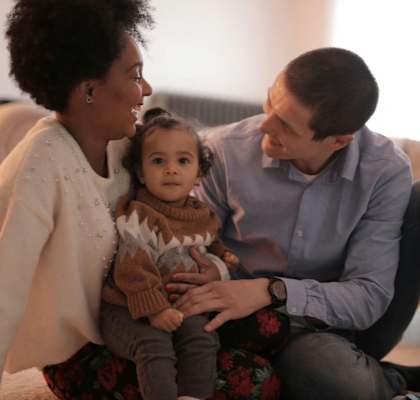 a man and woman sitting on the floor with a baby