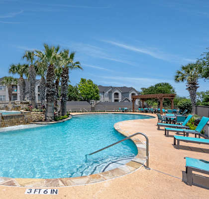 A swimming pool surrounded by palm trees and lounge chairs.