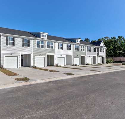 a two story house with white garage doors and a street
