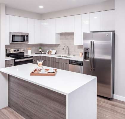 A modern kitchen with a white island and stainless steel appliances.