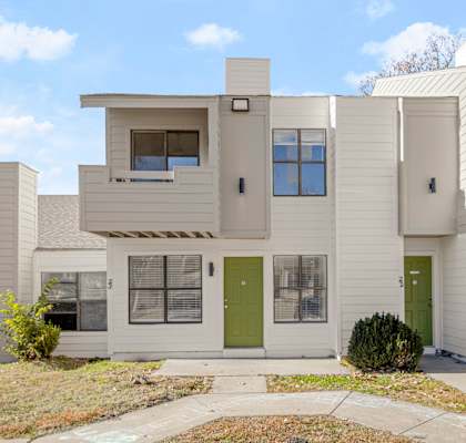 A white two story house with green doors.