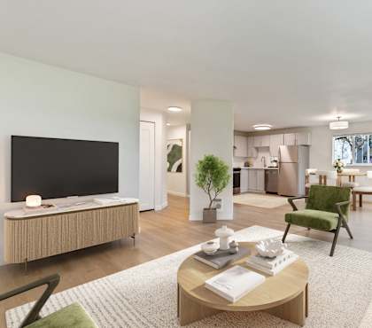 A modern living room with a flat screen TV, a green armchair, and a coffee table with a book and a cup on it.