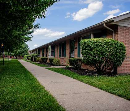 A long row of houses with green lawns and trees.