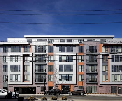 A modern multi-story building with a mix of white, black, and orange colors.