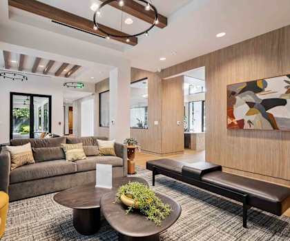 A modern living room with a large couch, a coffee table, and a painting on the wall.
