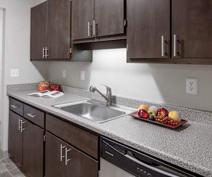 a kitchen with dark cabinets and a stainless steel sink