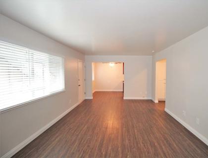 an empty living room with a large window and wood flooring