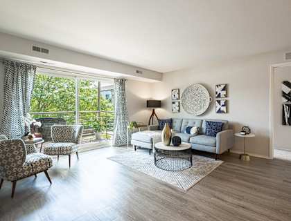a living room with a couch and chairs and a door to a balcony