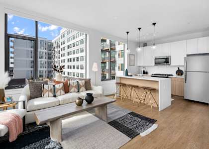 A modern living room with a large window and a kitchen area.