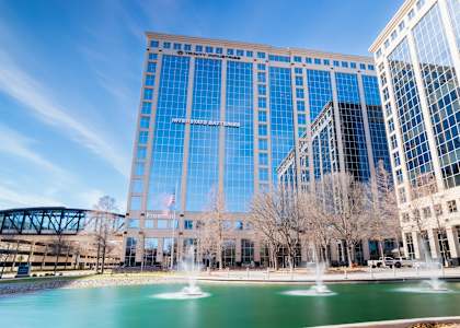 A large glass building with a fountain in front of it.