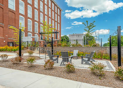 A small garden area with benches and a fence in front of a brick building.